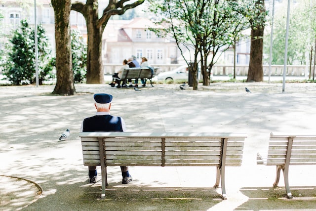 おじいさんが公園のベンチに一人で座っている