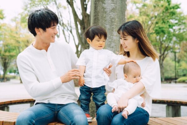 赤ちゃんの頭を撫でる男の子と両親