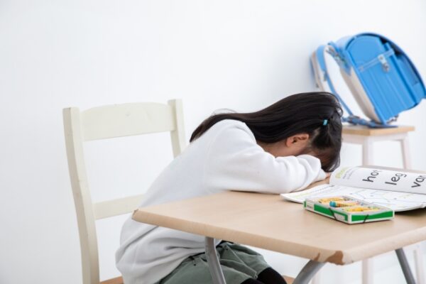 机に突っ伏す小学生の女の子