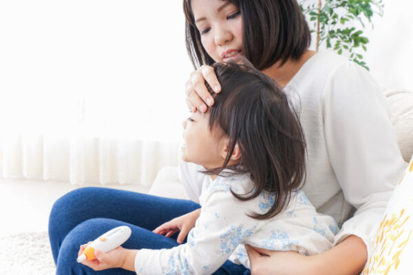 体調不良の子供の熱を測る女性