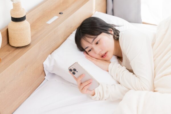 ベッドでスマホを見る女性