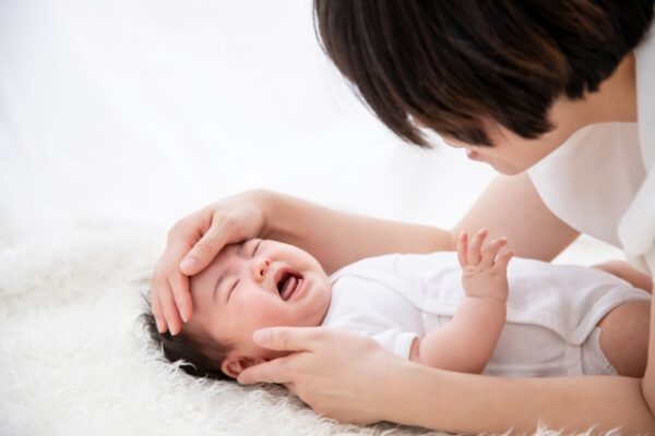 泣いている赤ちゃんの熱を測る母親
